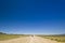 Traveller with backpack on a lonely road in desert