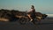 Traveller on a bike drives along the rocks on ocean surf line