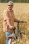 Traveller in cap and sunglasses with a bicycle at the field