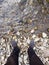 Traveller in dirty trousers and shoes standing on the rocks, rocky seaside / riverside, scene near a river First person pov