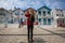 Traveller girl with blonde dreadlocks is takes photo on a smartphone striped houses in Costa Nova