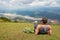 Traveller with gray backpack looking at sunny valley on background mountains