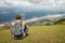 Traveller gray backpack resting enjoying the sunny valley of mountains in the background