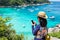 Traveller woman with colorful swimming suit use mobile take photo of view at top of mountain and speed boat in