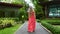 Traveller Woman in Red Dress Walking Barefoot on Path in Modern Tropical Resort