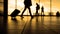 Travellers in airport walking to departures by escalator in front of window, silhouette, warm