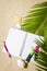 Travellers notebook with markers and pen on sand with palm tree leaf background, top view. Planning and ideas vacation concept.