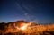 Travelling couple set up camp on night mountain lawn and stargazing together.