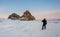 Travelling in winter, photographer carrying camera tripod at frozen lake Baikal in Siberia, Russia