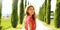 Travels in Tuscany. Close up of beautiful girl in Tuscany. Young fashion woman walking in cypresses lane on sunny day. Panoramic