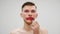 Travesty man applying lipstick on lips. Man smearing makeup on face. Portrait of transsexual guy applies pink lipstick and smearin