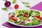 Trawberry, baby spinach, red onion, goat cheese and avocado salad on a white dish on a table mat