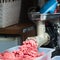 Tray of chopped meat, meat mincer, butcher`s hand.