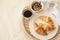 Tray with coffee cup, croissants, muesli and white flowers