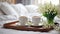 Tray cups of coffee, vase with lily of the valley flowers on the bed in the bedroom