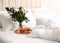 Tray with cups of tea and floral decor near soft blanket on bed