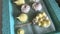 On a tray lies a freshly prepared marshmallow of various shapes, colors and sizes. A woman uses a pastry bag and nozzle to apply