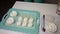 On a tray lies a marshmallow in the form of a rose. A woman with the help of a pastry bag forms a classic-shaped marshmallow next