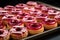 a tray of semi-finished donuts waiting to be filled with jelly