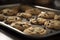 A tray of warm, freshly baked chocolate chip cookies with gooey, melted chocolate chips oozing out of every bite.