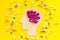 Treat brain diseases. Head with plastiline meanders and pills on yellow background top view