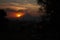 Tree branches heading towards the sun hiding behind volcano at dusk in Puebla Mexico dramatic Twilight