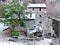 Tree in front of a stone house with a roof covered with frost on the mountainside, along the trada that leads to the lake of Isola