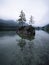 Tree island reflection in alpine mountain lake Hintersee cloudy mood Ramsau Berchtesgadener Land Bavaria Germany