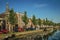 Tree-lined canal with boat, church bell tower and brick houses at the bank on sunset in Weesp.