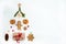 The tree is made of gingerbread, gift boxes, slices of dried apples, cones, walnuts, candy and straw toys on a white background. C