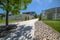 Tree in the middle of a concrete and stone pathway against homes and blue sky