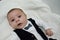 Tree months old newborn baby boy dressed like businessman with bow tie, face expresion