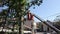 Tree pruning and sawing by a man with a chainsaw, standing on a platform of a mechanical chair lift