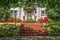 Tree shaded dappled sidewalk and sloped lawn in front of upscale stucco house with wreath and azaleas and brick steps - beautiful