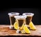 Tree shot glasses of Mexican tequila cocktail with lemon slices and salt on wooden table with black background