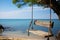 A tree suspended wooden swing with a backdrop of the azure sea