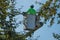 Tree trimmer in bucket holding a chainsaw