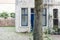 Tree trunk in front of old white colored house in dutch city Deventer. Overijssel, Netherlands.