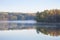 Trees in autumn color on a misty calm lake in northern Minnesota at dawn