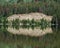 Trees and cliff reflected in still lake