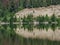 Trees and cliff reflected in still lake