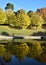 Trees with colored leaves, which are reflected in the pool water in autumn, inside the Boboli Gardens in Florence.