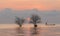 Trees and fisherman in the lake with beautiful sunrise and sky.