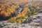 Trees in full autumn color and a small river viewed from rocky o