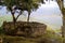 The trees growing inside rounded house ruins of Kuelap mountaintop citadel with the rainbow of lower hill in background, Peru