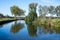 Trees reflecting in the blue water of the river Dender, Zandbergen, Flemish Region, Belgium