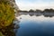 Trees by a river bank. Rich saturated color. Blue sky reflection in water. Fog over water surface. Stunning nature background