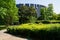 Trees and shrubs before modern building at sunny summer noon