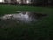 Trees and Sky Reflected in a Large Puddle in a Partly Flooded Play Park