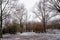 Trees sprinkled with snow drifts in an ice cold, depressing mood city park in Germany.